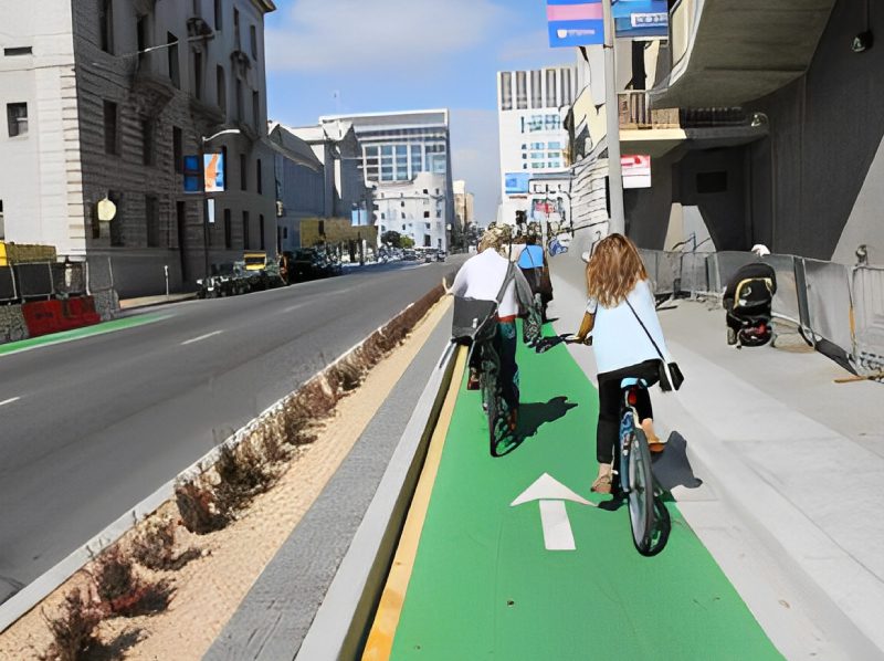 A group of people riding bikes on the side of a street.